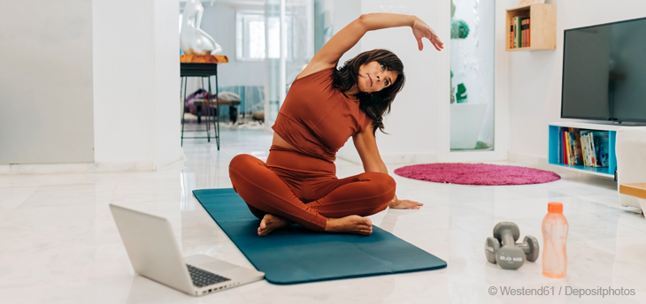 Eine reife Frau macht zu Hause Yoga-Übungen