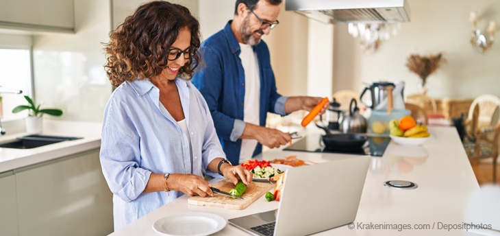 Ein reifes Paar kocht lächelnd gemeinsam in der Küche