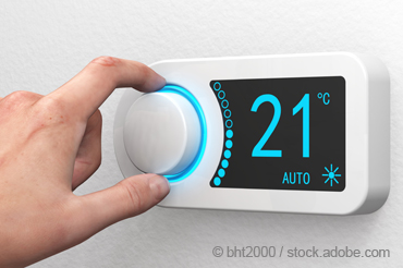 Männliche Hand dreht das Heizungsthermostat auf 21 Grad