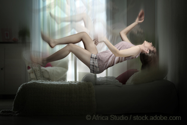 Eine junge Frau fällt schwebend auf ihr Bett zurück