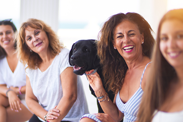 Vier Frauen unterschiedlichen Alters und ein Hund lächeln in die Kamera