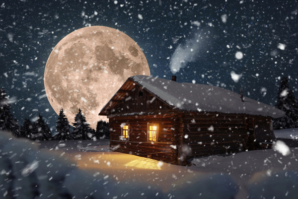 Eine junge erkältete Frau sitzt in einem weihnachtlich geschmückten Zimmer auf einer Couch