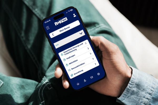 Ein Mann hält die R+V-BKK-App in der Hand